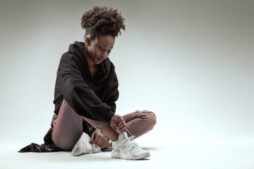 Relaxed young woman with a gentle look sits comfortably in jeans and hoodie