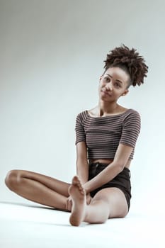 Comfortable in her style, a young woman lounges with a soft expression
