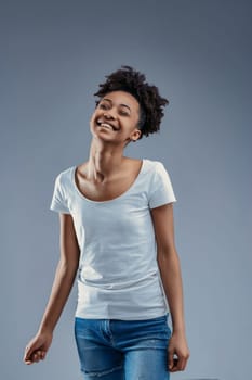 Delightful young woman enjoys a light moment, her afro and casual style epitomizing relaxed joy