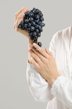 Unrecognizable woman holds a bunch of ripe grapes in her hand