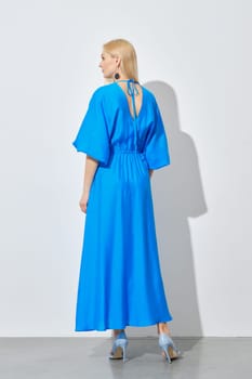 Back view of blonde woman in vibrant long blue dress
