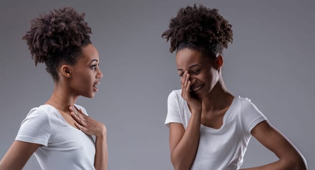 black woman engaged in self-gossip, her reflection's grin shows delight in the shared secret