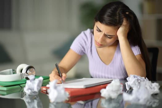 Frustrated student crumpling papers trying to do a homework in the night at home