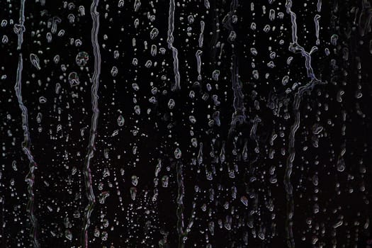 Drops of water or rain spread over a black background in close-up