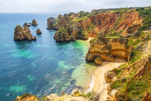 The rugged coastline where cliffs meet the shimmering Atlantic Ocean, overlooking Praia do Camilo, famous beach near Lagos in the Algarve, Portugal