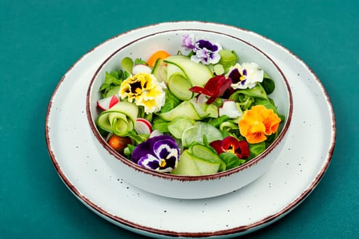 Spring natural salad of fresh vegetables and decorated with edible flowers.