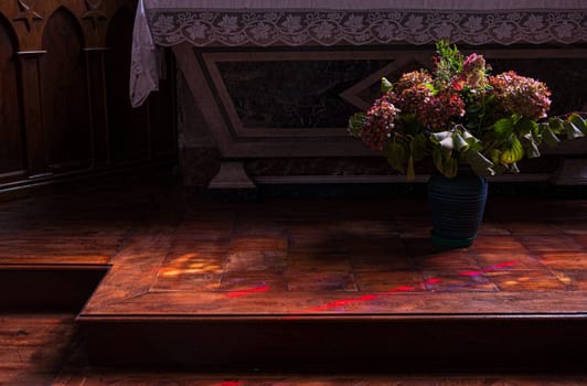 Flowers at the foot of the church altar. Dark atmosphere of contemplation. Photography taken in France