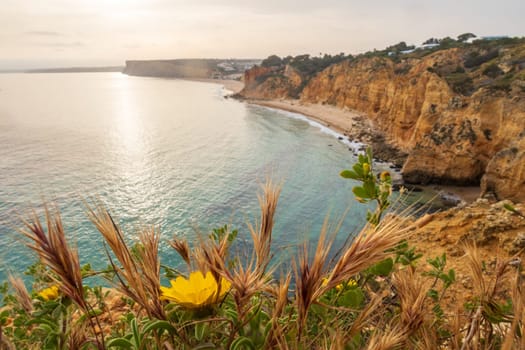 The rugged coastline where cliffs meet the shimmering Atlantic Ocean at dawn, overlooking beach near Lagos in the Algarve, Portugal