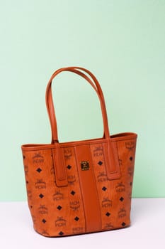 Berlin, Germany – March 29, 2024. Close-up of luxury expensive brown MCM leather handbag on a bright glitter sparkle background.