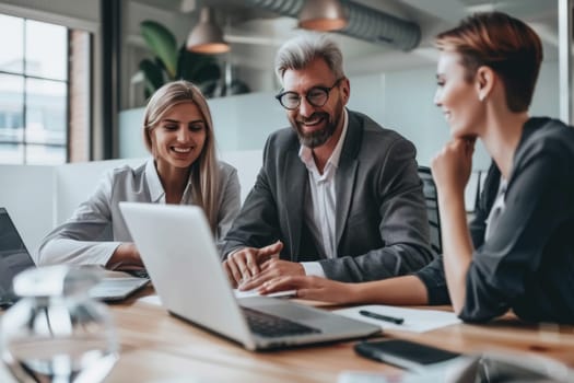 Business professionals smiling while discussing work at a contemporary office desk with a laptop