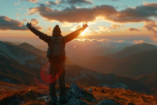 Man celebrating with arms raised at the summit during a stunning sunset landscape