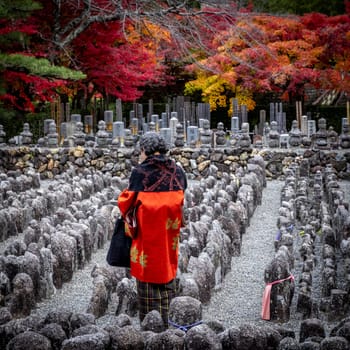 KYOTO/JAPAN - November 27, 2023:Elderly woman prays in the Adashino Nenbutsuji cemetery