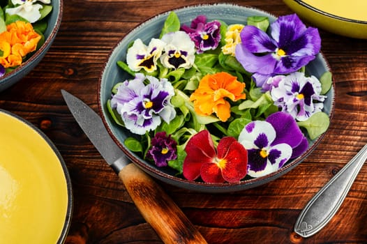 Plate with detox seasonal colorful edible flower salad. Copy space.