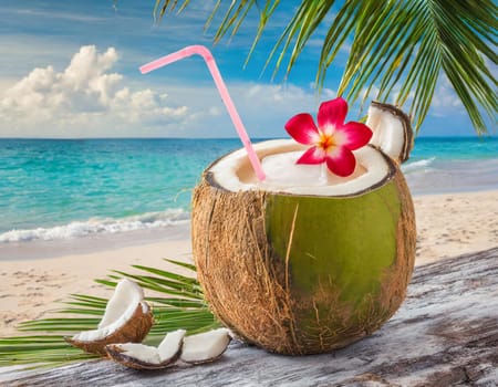 A coconut cocktail with a straw on the palm beach