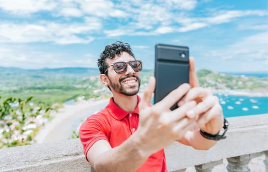 Happy tourist man taking a selfie at a beach viewpoint. Handsome man taking a selfie at the viewpoint of San Juan del Sur