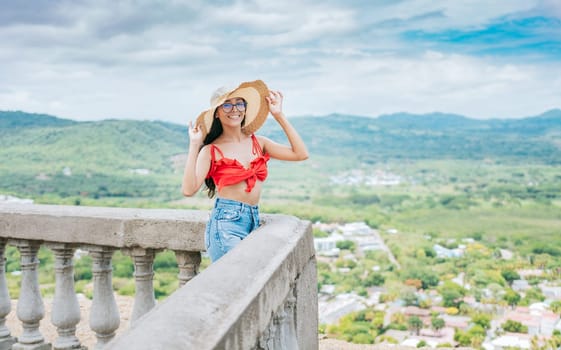 Portrait of beautiful tourist girl in a viewpoint. Happy vacationer woman in hat on a viewpoint. Travel and tourism promotion concept