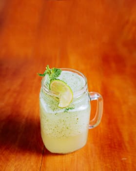Refreshing lemonade with mint on wooden table. Lemonade drink on wooden background
