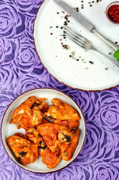 Baked chicken wings with chili sauce on rustic wooden table. Space for text.