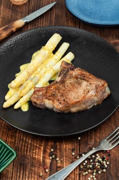 Juicy fried meat steak with boiled white asparagus.