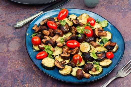 Mushrooms, zucchini and tomatoes baked in the oven on rustic wooden table. Copy space.