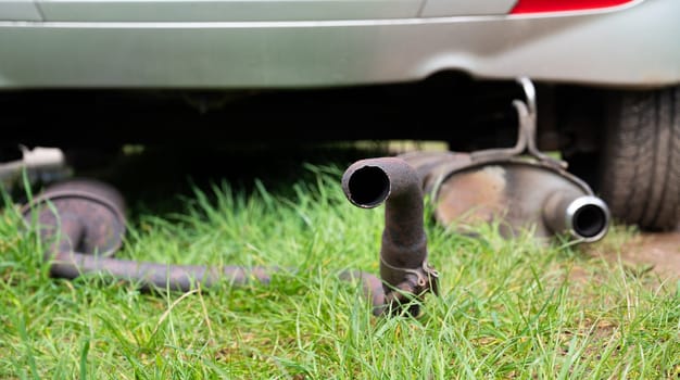Broken exhaust and muffler of a car, rusted silencer fallen down on the road, breakdown of vehicle