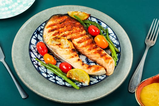 Fried salmon steak and grilled potatoes and green beans. Grilled fish.