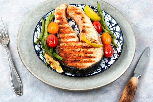 Fried salmon steak and grilled potatoes and green beans. Grilled fish.