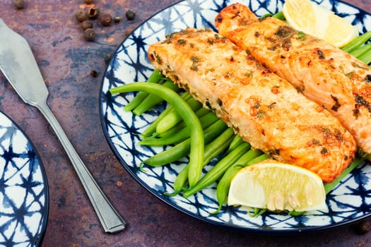Tasty roasted salmon fish with bush green beans on the plate. Paleo, keto diet. Space for text.