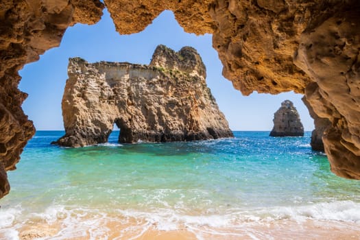 Small, heavenly and difficult to access beach photographed from inside a cave, near Portimão in the Algarve region of Portugal