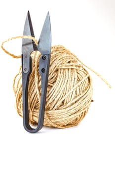 Scissors and a ball of twine on a white background. Selective focus with shallow depth of field.