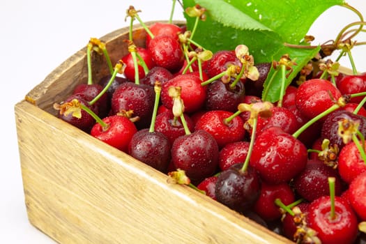 Ripe red cherries in a small wooden crate. Selective focus with shallow depth of field.