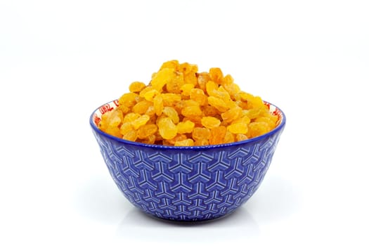 Dried golden raisins in a porcelain bowl. Selective focus with shallow depth of field.