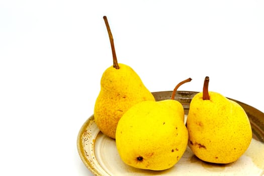Yellow pears in a group in a ceramic plate. Selective focus with shallow depth of field.
