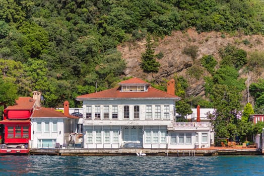 View from Bosphorus strait of the green mountains of the Asian side, with traditional houses and dense trees in a summer day, Istanbul, Turkey