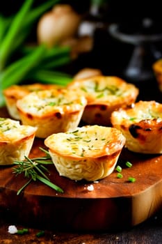 Board with delicious meat tartlets on wooden board.