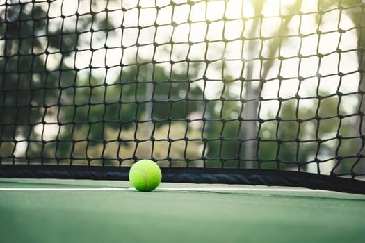 Tennis ball on tennis court with net in background