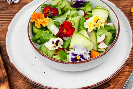 Raw fresh salad of cucumber, radish, green and flowers. Clean and healthy eating concept. Space for text.