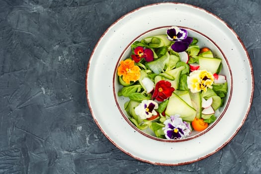 Raw fresh salad of cucumber, radish, green and flowers. Clean and healthy eating concept. Space for text.
