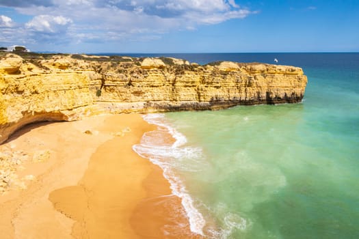 View over cliffs and ocean waves crashing onto Praia da Ponta Pequena beach near Albufeira, Algarve, Portugal