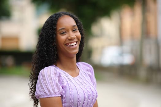 Happy black woman laughing looking at camera standing in the street