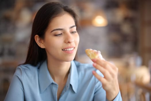 Woman in a restaurant interior eating bakery