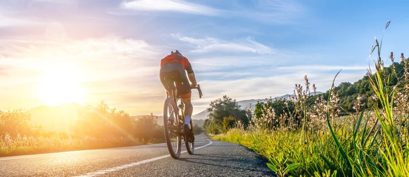 Mature Adult on a racing bike climbing the hill at mediterranean sea landscape coastal mountain road - mallorca mountains