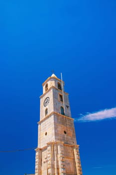 SYMI, Greece - 03 June 2021 The top of the imposing clock tower (Roloi), which stands right at the entrance to the port of Symi. Next to it the police station building.