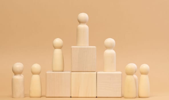 Wooden figures of men stand on a pedestal. The concept of rivalry in sports, business and life. Achieving success and leadership