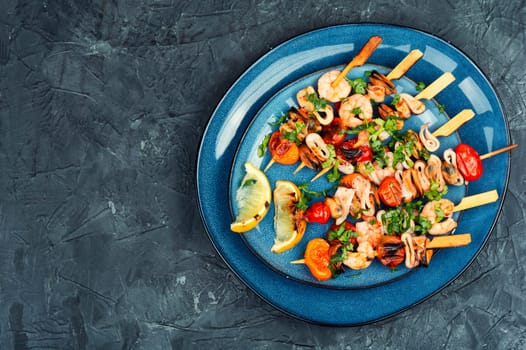 Barbecue or grilled seafood kebabs, shrimps prawns, mussels and grilled squid on skewers. Space for text.