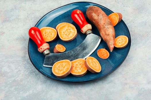 Sweet potatoes or batatas, board and knife . Dietary food. Vegetables.