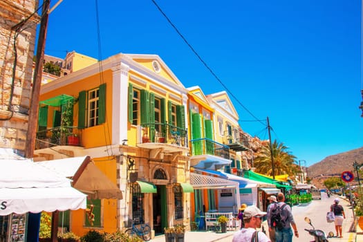 SYMI, Greece - Jun 03, 2021. Tourists on the harbour promenade of Symi town. Most beautiful and romantic district in the whole Aegean.
