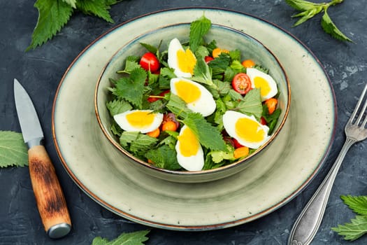 Bowl with salad of nettle leaves, eggs and tomatoes. Healthy spring detox food.