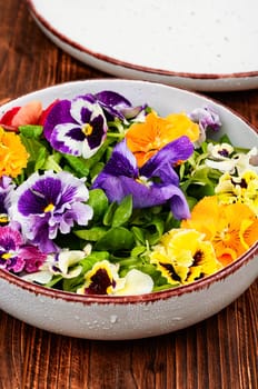 Plate with detox seasonal colorful edible flower salad.