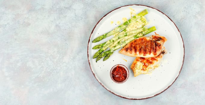 Roasted or grilled chicken breasts with green asparagus. Grilled meat and asparagus. Space for text.